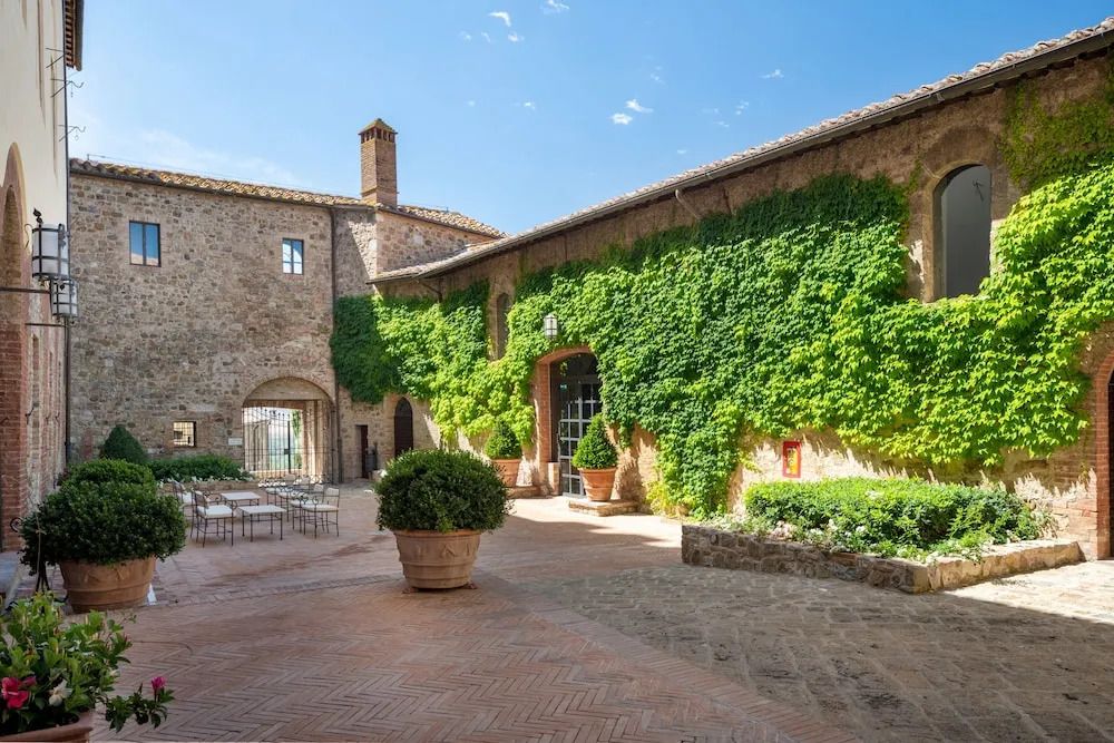 Historischer Innenhof mit grün bewachsener Steinmauer und Terrakotta-Fliesen.