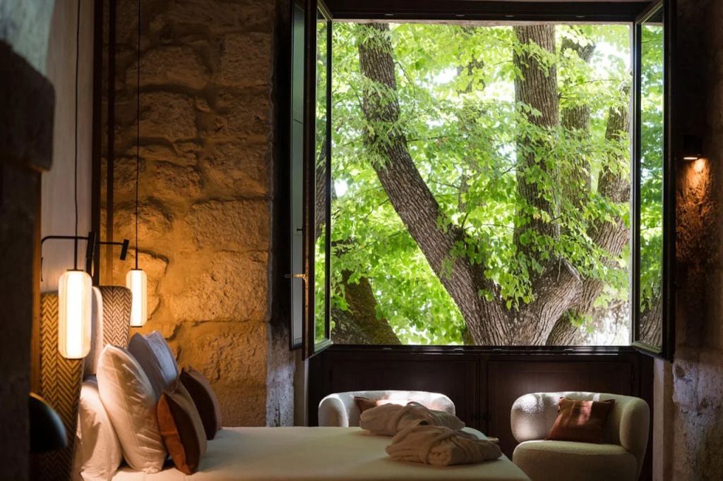 Gemütliches Zimmer mit großen Fenstern und Blick auf grüne Bäume