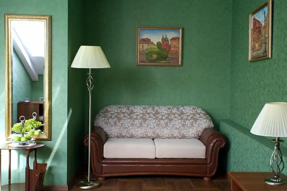 Stilvoll eingerichteter Wohnbereich mit grünem Sofa und Stehlampe