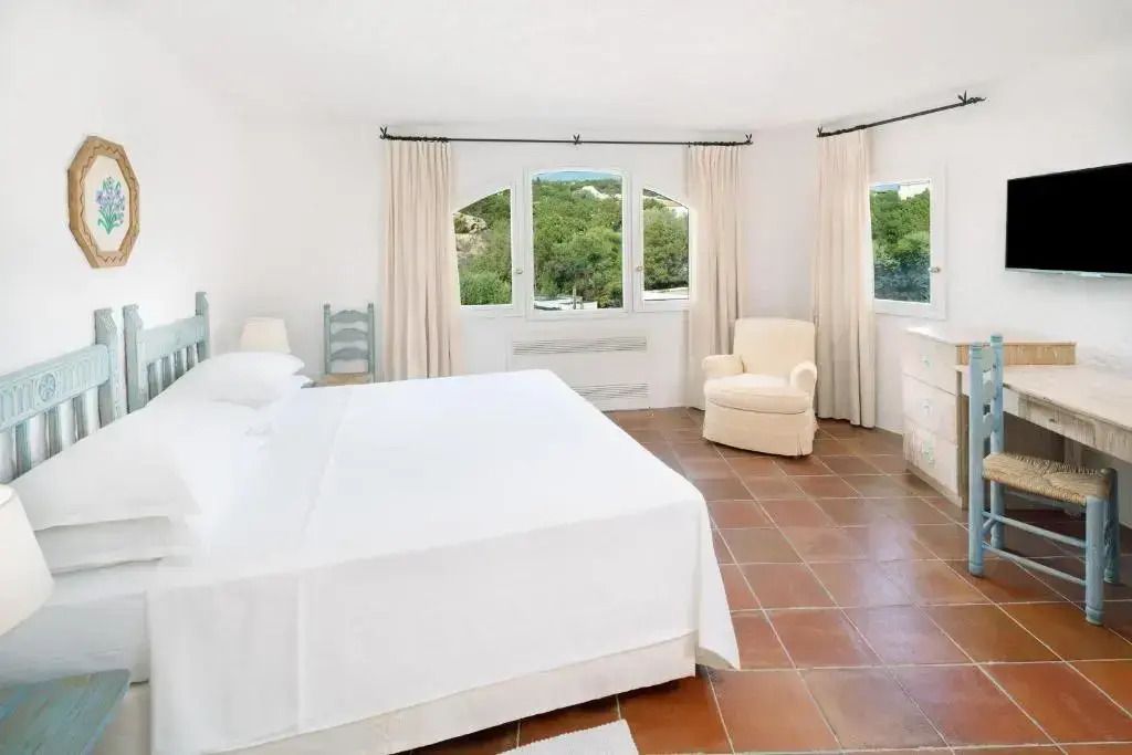 Helles Zimmer mit großem Bett und Fenstern mit Blick ins Grüne