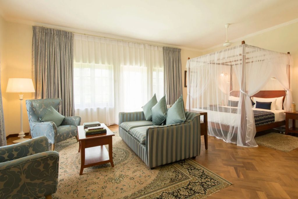 Eleganter Wohnbereich mit klassischem Sofa und Himmelbett in heller Suite