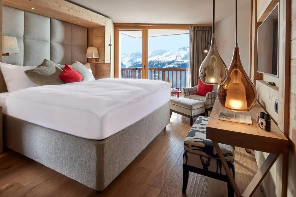 Elegantes Hotelzimmer mit großem Bett und Blick auf schneebedeckte Berge