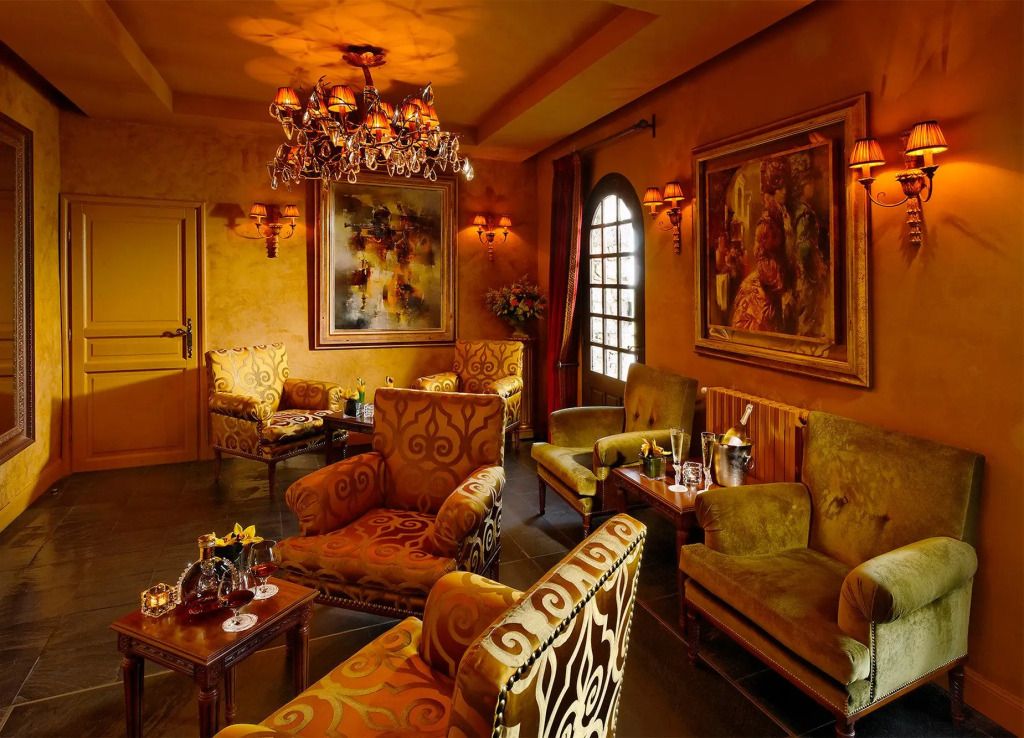 Gemütliche Lounge mit stilvollen Sesseln, Gemälden und Kronleuchter im Château Eza Hotel