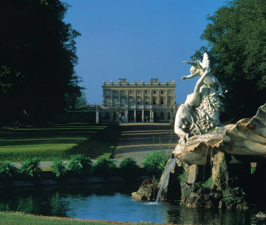 Historische Fassade von Cliveden House vor einem Brunnen mit Skulptur im Park.