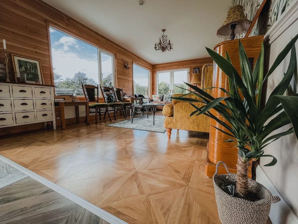 Heller Raum mit großen Fenstern, gemütlichen Sesseln und Parkettboden