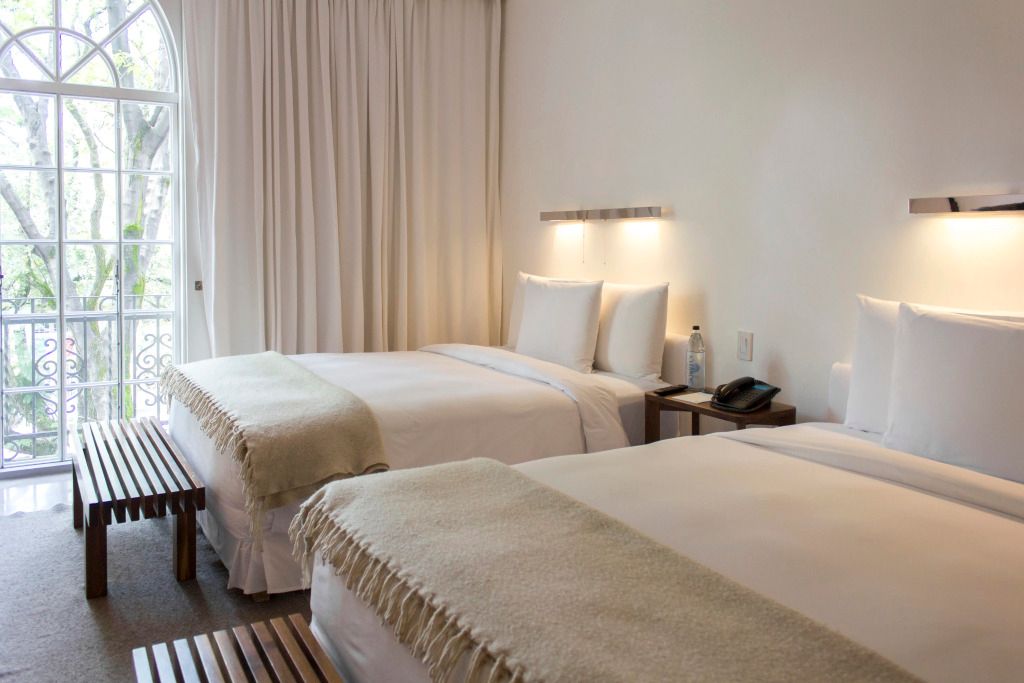 Modernes Hotelzimmer mit zwei Betten und weißer Einrichtung