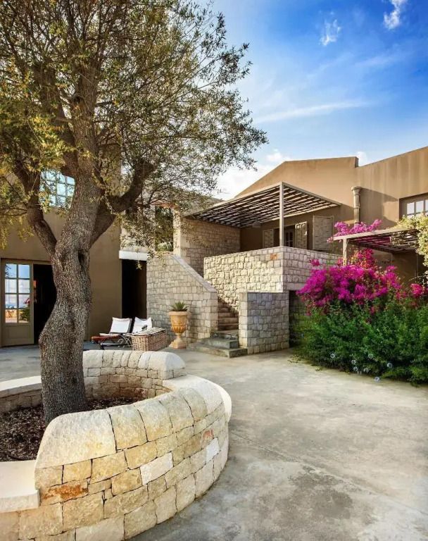 Steinverkleidetes Gebäude mit Terrasse und blühender Bougainvillea