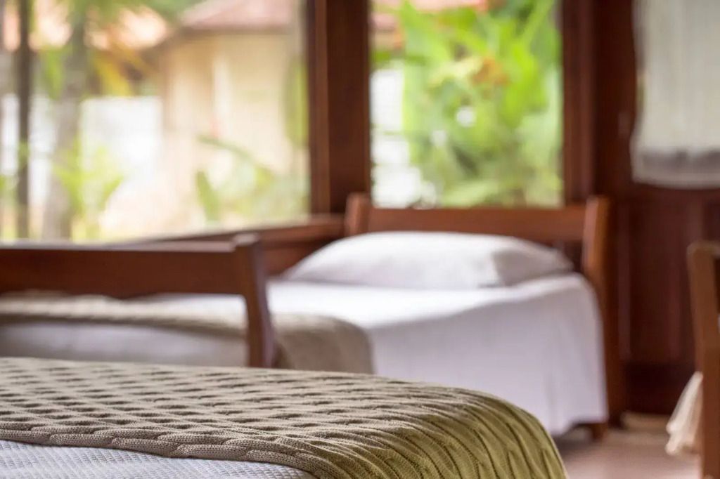 Gemütliches Hotelzimmer mit Blick auf den Garten durch große Fenster.