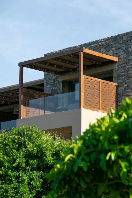 Moderne Hotelterrasse mit Holzdach und Glasgeländer. Grüne Pflanzen im Vordergrund.