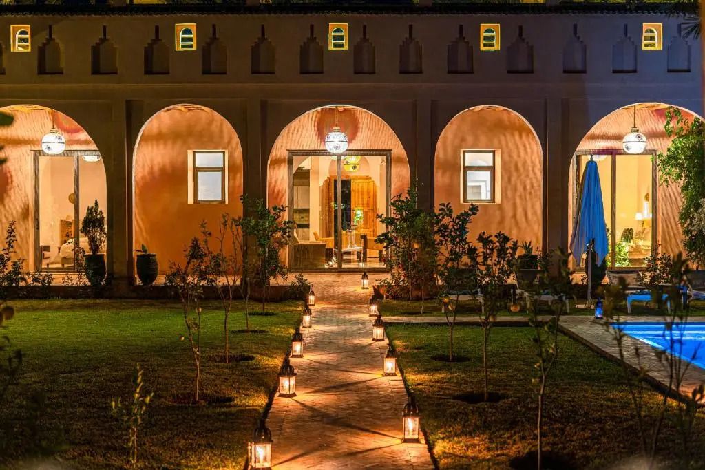 Eingangsbereich des Dar Hnini Hotels mit beleuchtetem Gartenweg am Abend