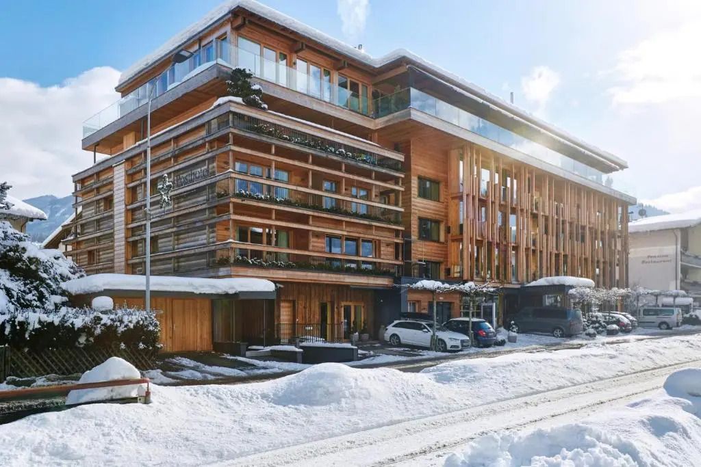 Schnee bedeckte Fassade des Holzhotels mit moderner Architektur