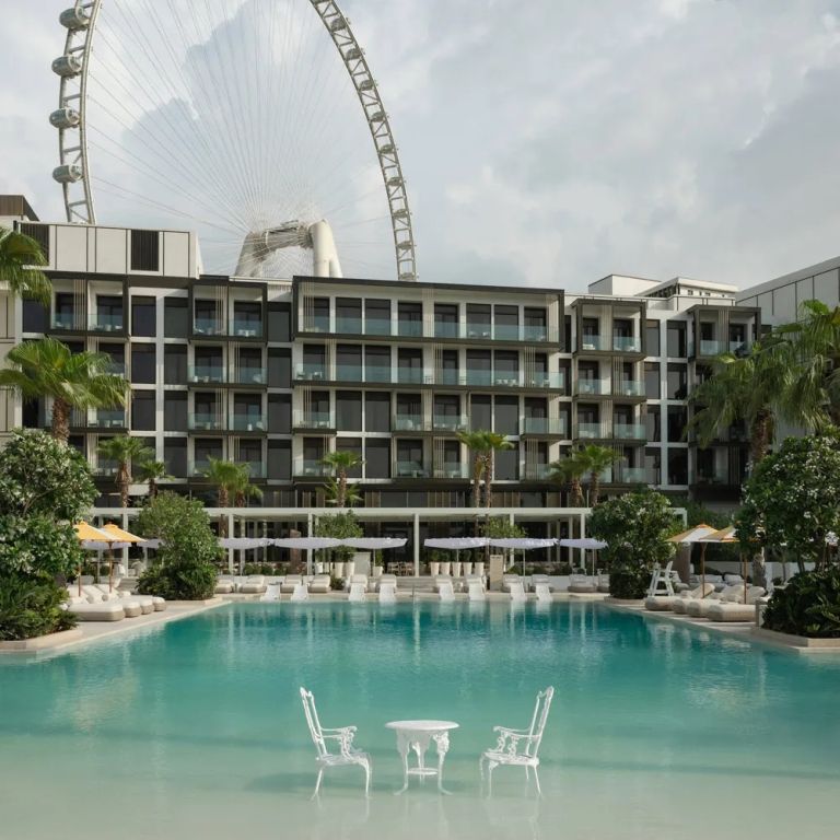 Moderner Hotelpool mit Blick auf ein großes Riesenrad im Hintergrund