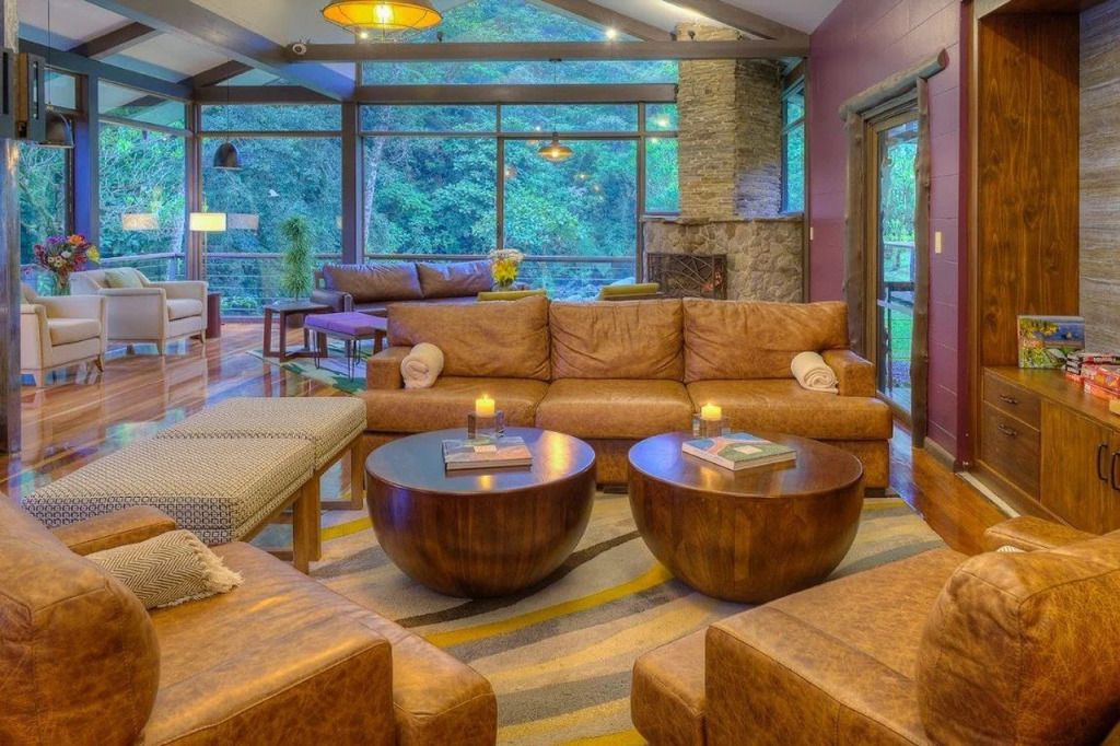 Lounge mit Ledersofas und Holzdekor vor großen Fenstern mit Blick ins Grüne