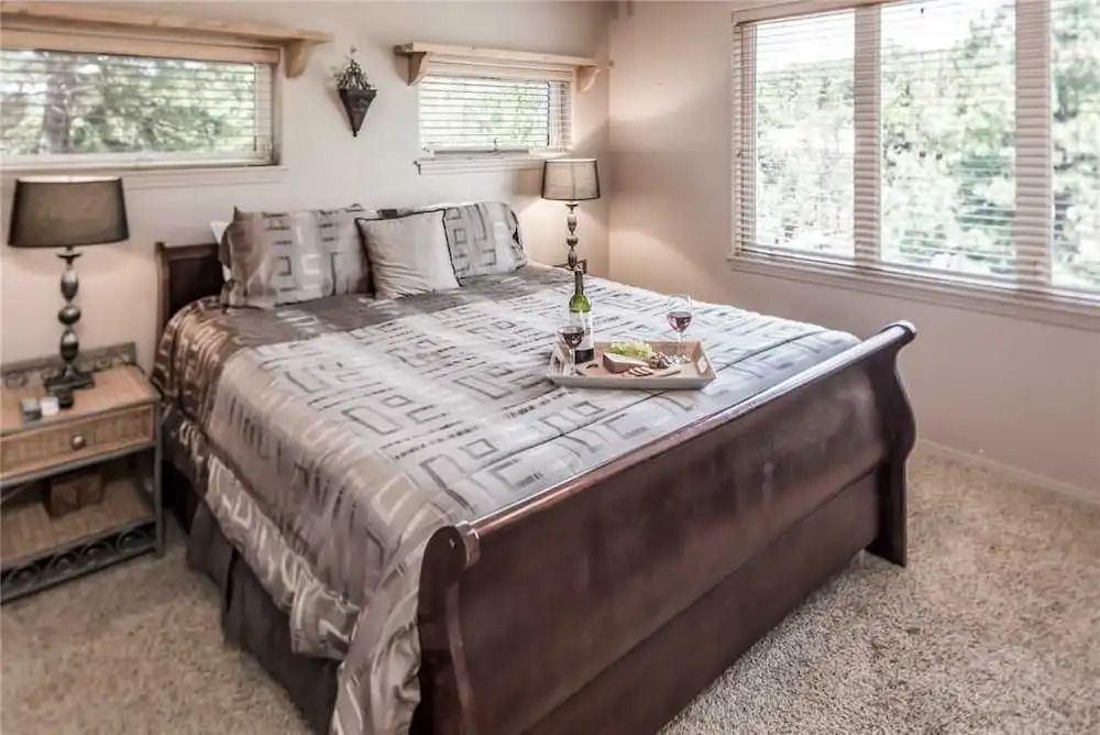 Gemütliches Schlafzimmer mit großem Bett und zwei Fenstern mit Blick ins Grüne