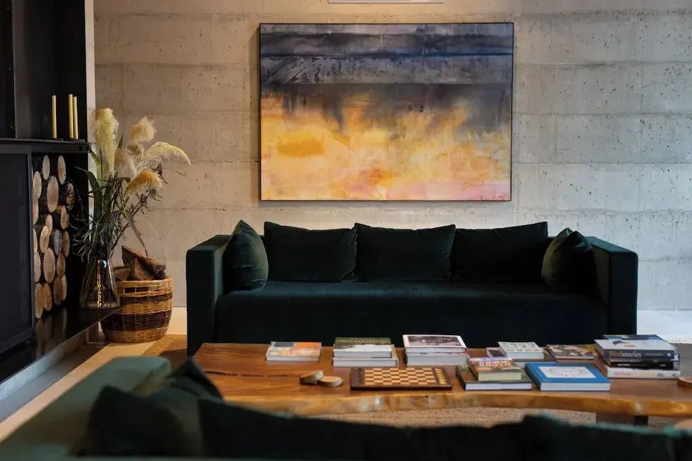 Elegante Lounge mit dunkelgrünem Sofa und Kunst an der Wand
