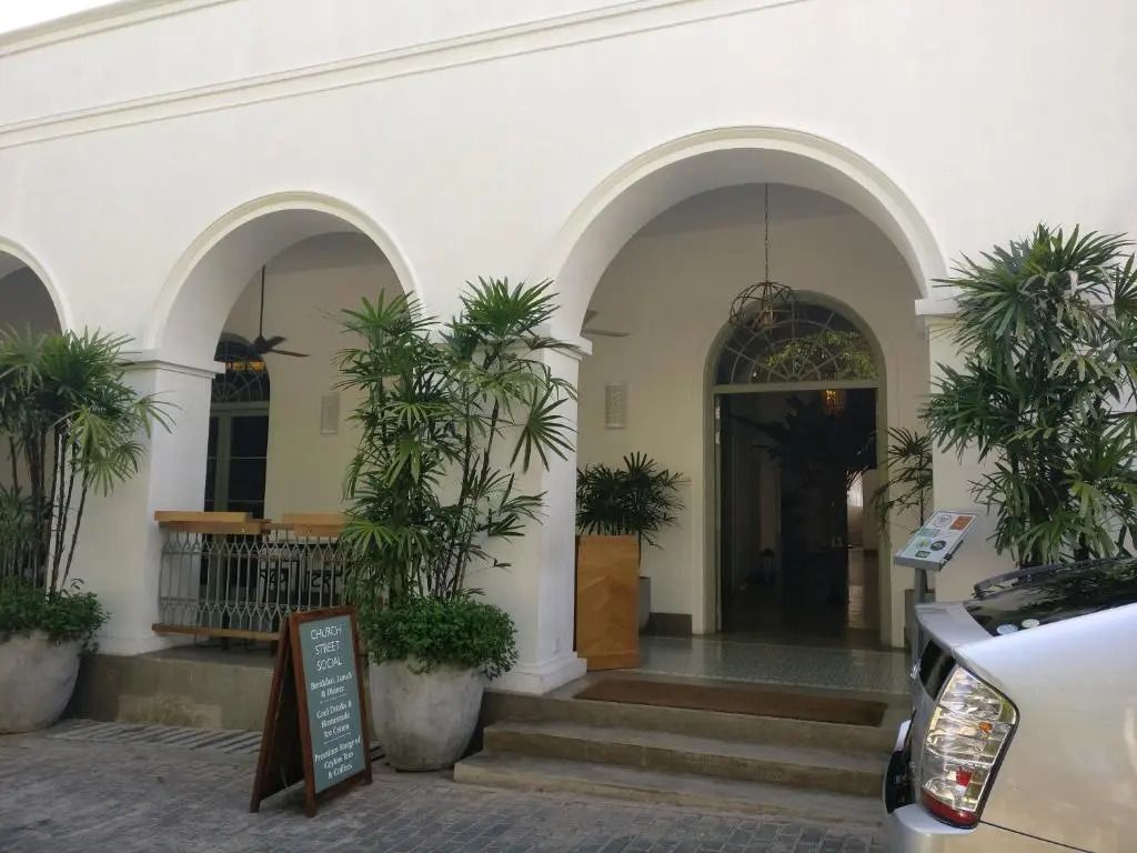 Elegante Eingangsfassade des Hotels mit weißen Bögen und Pflanzen