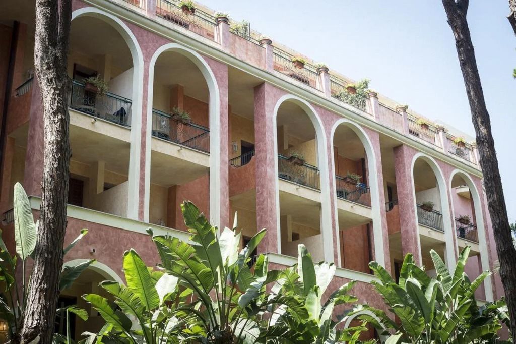Hotel Il Castello Fassade mit üppiger Vegetation und rosa Bögen