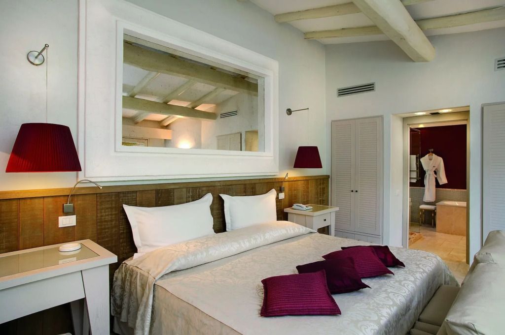 Elegantes Hotelzimmer mit Holzbalkendecke und roten Akzenten im Forte Village Resort.