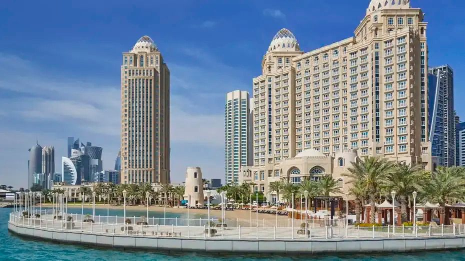 Außenansicht des Four Seasons Hotel Doha mit türkisfarbenem Wasser im Vordergrund