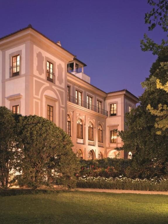 Außenansicht des Four Seasons Hotel Firenze bei Abenddämmerung mit gepflegten Gärten