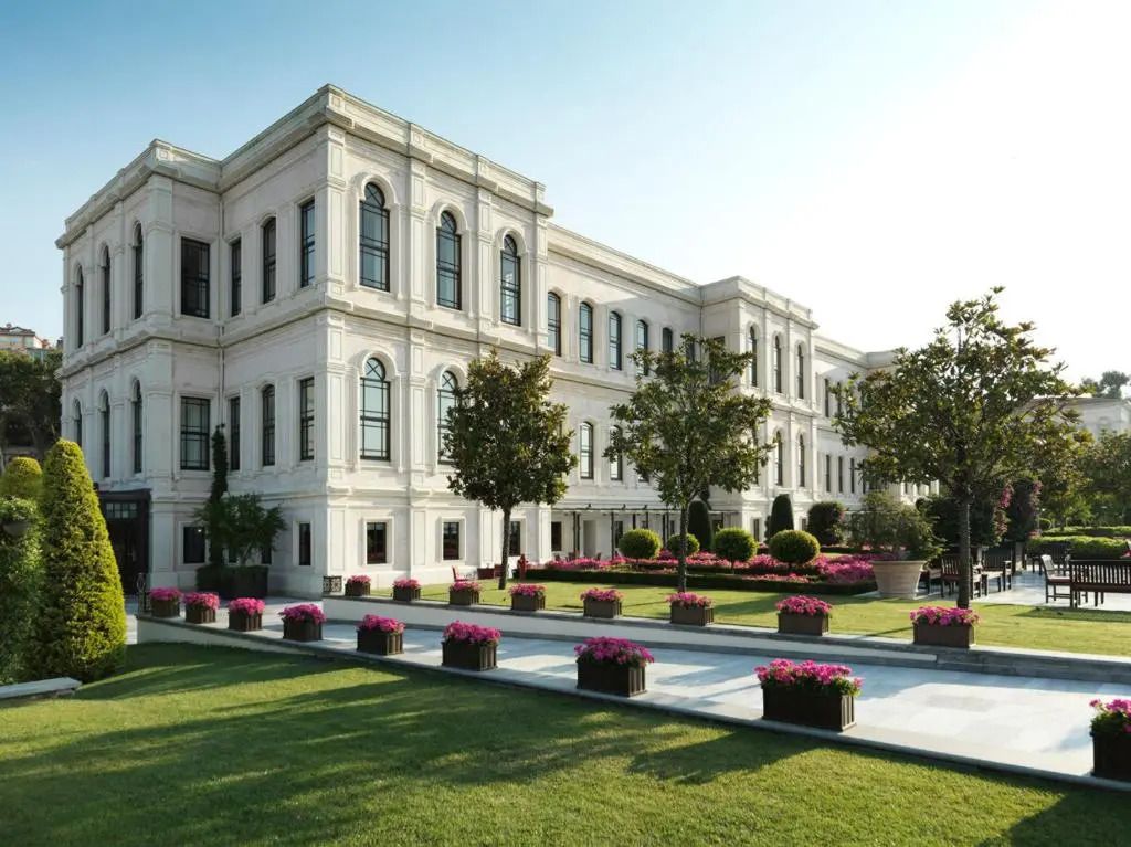 Historische Fassade des Four Seasons Hotel Istanbul mit gepflegtem Garten und Blumenarrangement.