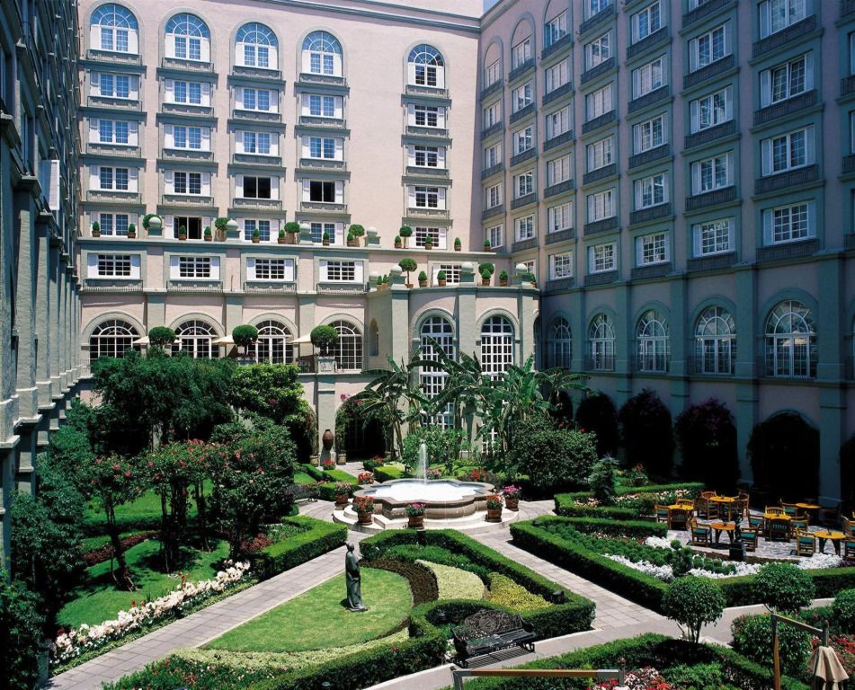 Eleganter Garten mit Brunnen und beeindruckender Hotelfassade im Hintergrund