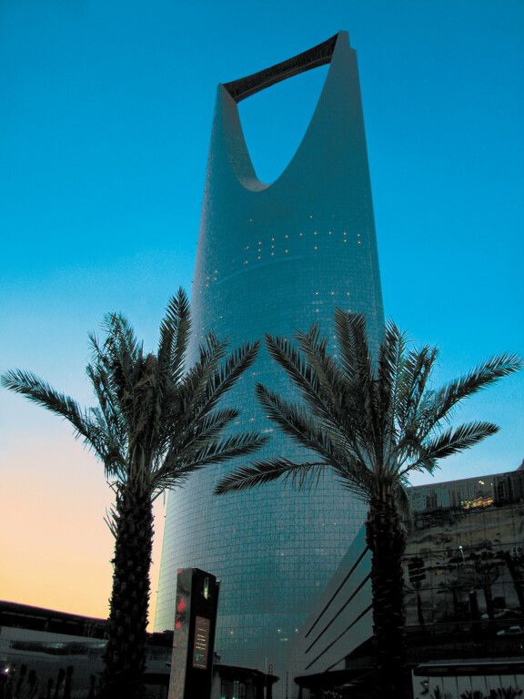 Architektonische Fassade des Four Seasons Hotel Riyadh bei Sonnenuntergang mit Palmen.