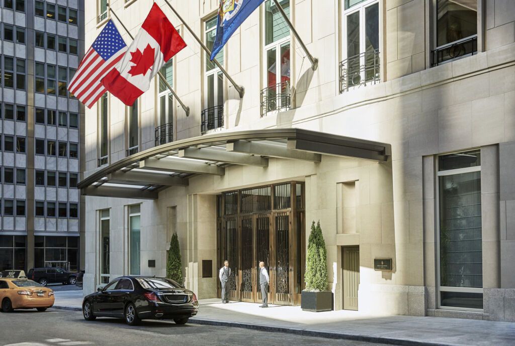 Hoteleingang mit Fahnen und schwarzem Auto davor