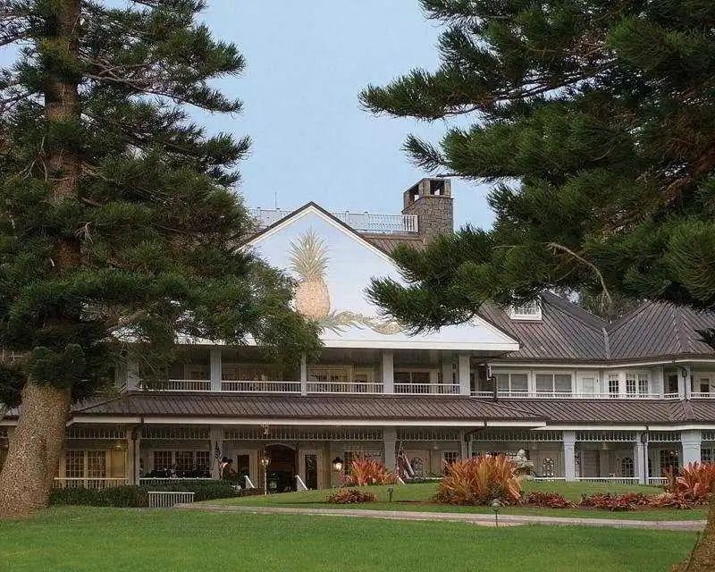 Hoteleingang mit gepflegtem Rasen und hohen Bäumen bei Dämmerung