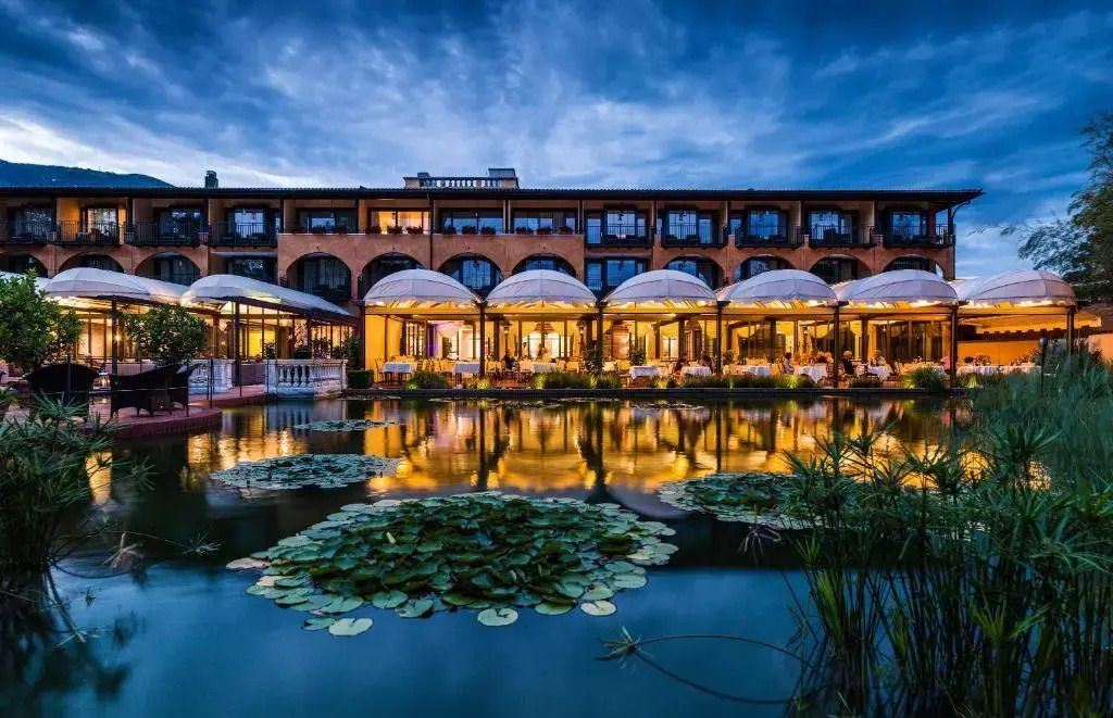 Elegante Hotelarchitektur bei Dämmerung mit beleuchtetem Wassergarten und Seerosen