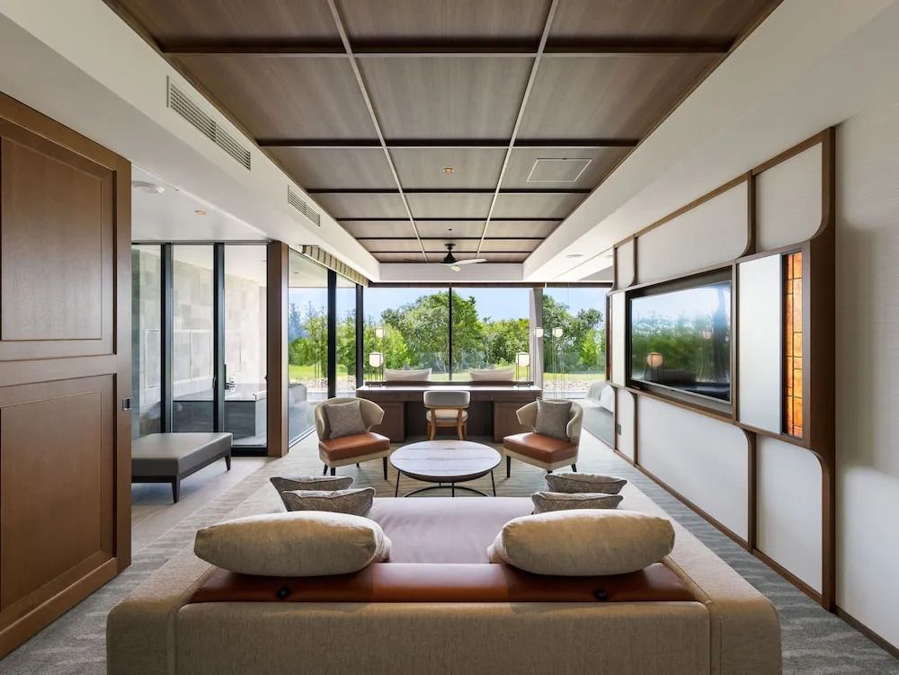 Modernes Wohnzimmer mit Glasfront und Blick auf grünen Garten im Luxushotel