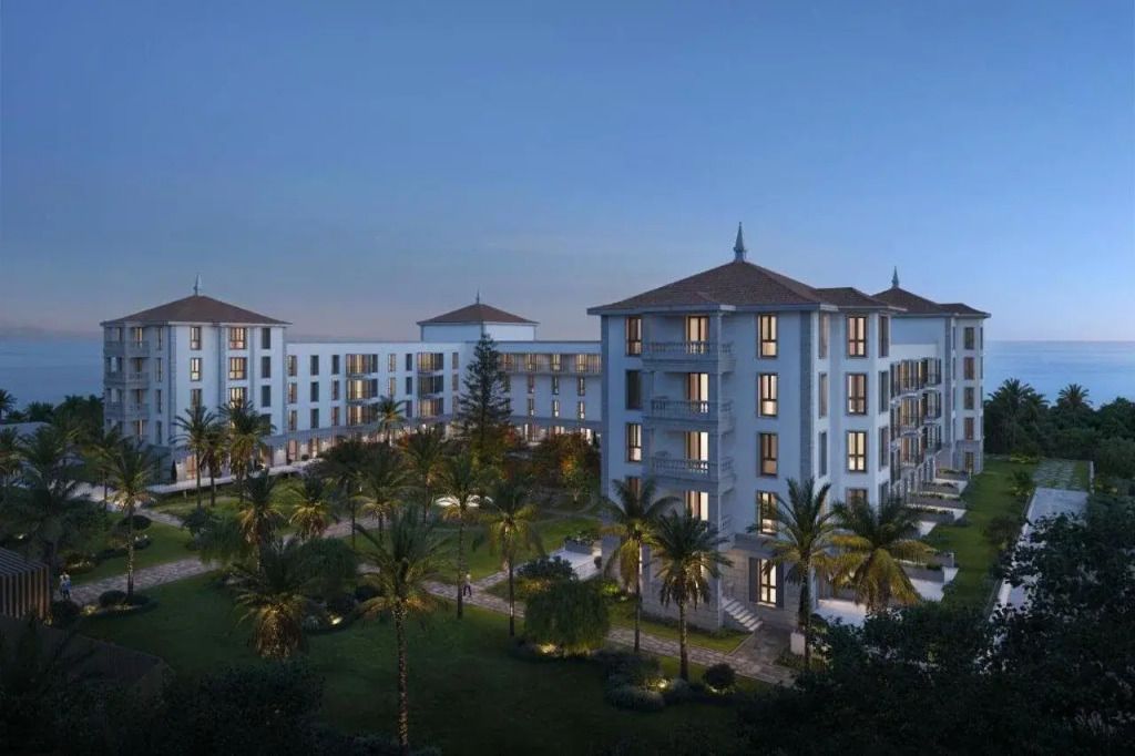 Hoteleingang und Gartenanlage bei Abenddämmerung mit beleuchteten Fenstern