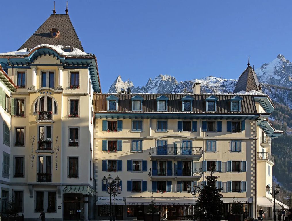 Historische Fassade des Grand Hôtel Des Alpes mit verschneiten Bergen im Hintergrund