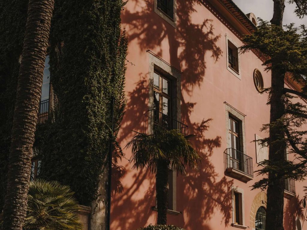 Charmante rosa Fassade des Grand Hotel Son Net mit efeubewachsenen Wänden und Palmen.