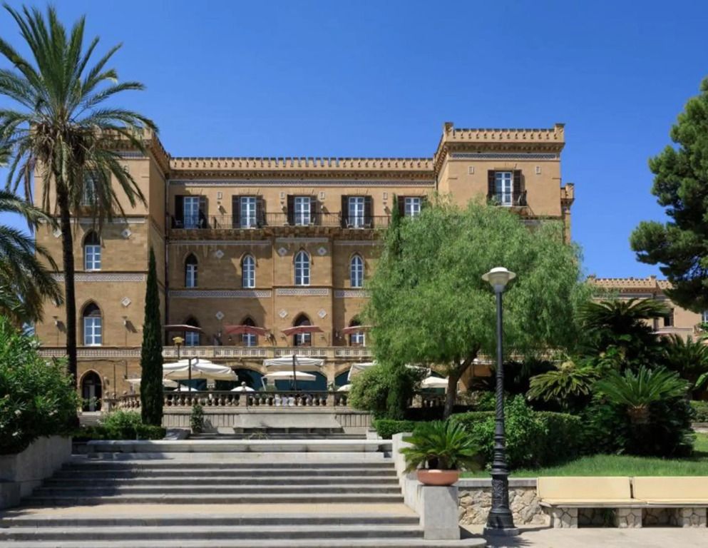 Historische Fassade des Verdura Resorts mit Palmen und üppigem Garten