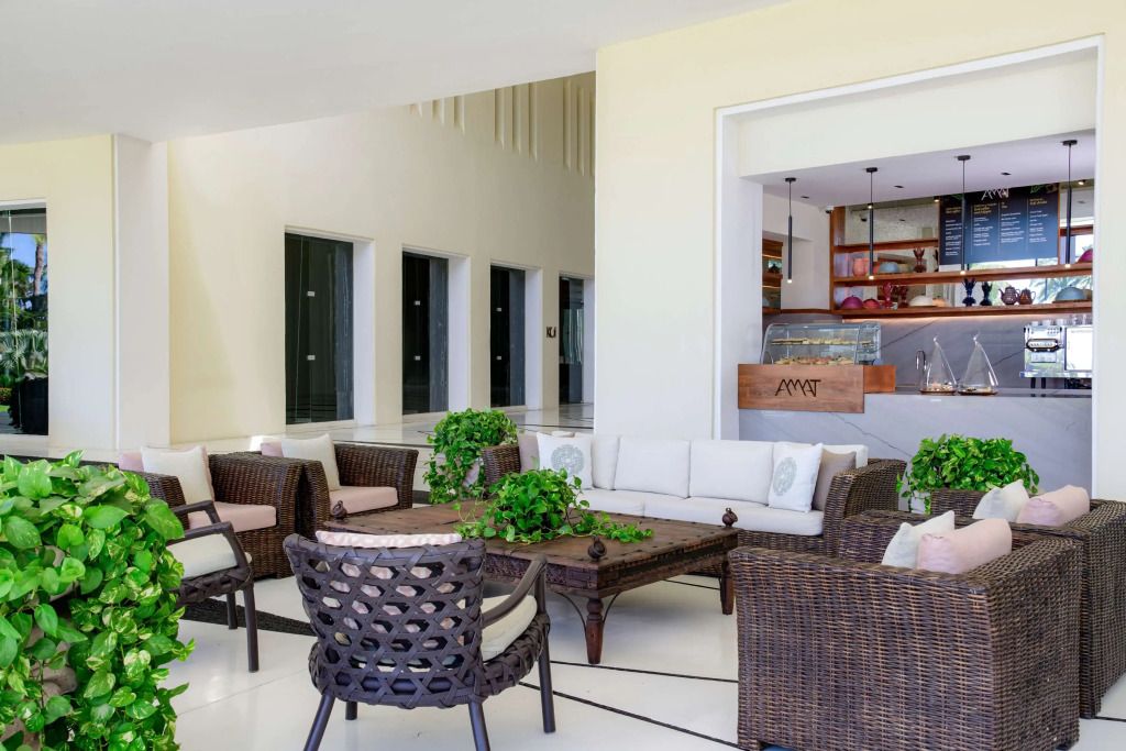 Elegante Hotellounge mit Rattanmöbeln und grünen Pflanzen.