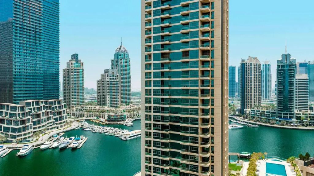 Blick auf die Fassade eines modernen Hochhauses mit Yachthafen im Hintergrund