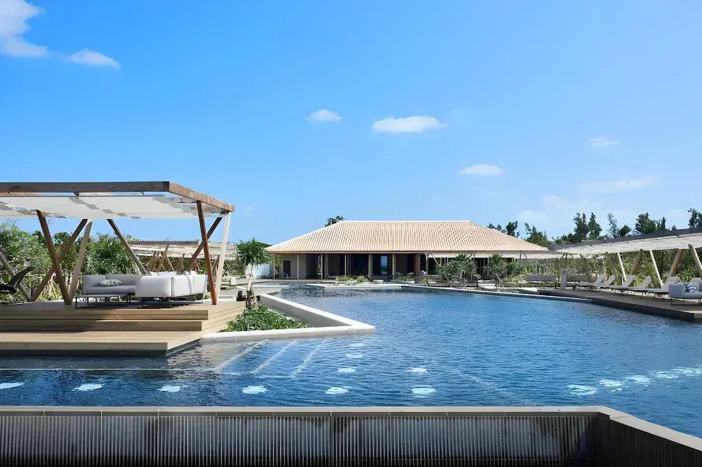 Luxuriöser Poolbereich mit Liegen und moderner Architektur unter klarem Himmel.