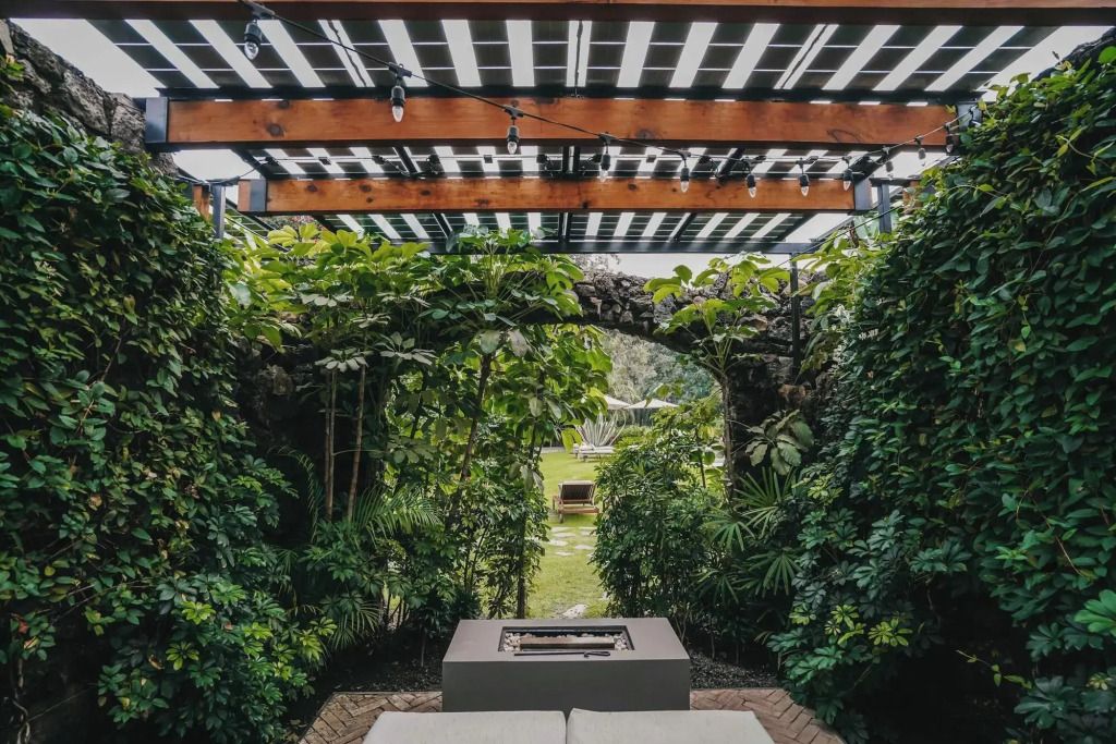Üppig bepflanzter Außenbereich mit Sitzgelegenheit unter Holzdach