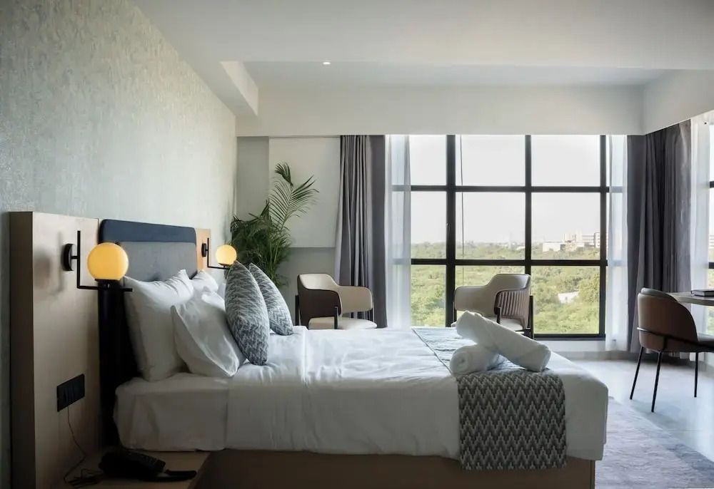 Helles Hotelzimmer mit großem Fenster und grünem Ausblick