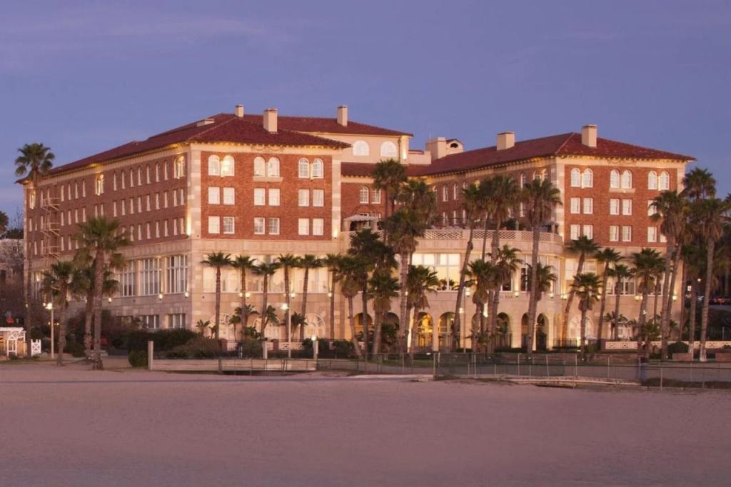 Fassade des Hotels Casa Del Mar bei Abenddämmerung mit Palmen im Vordergrund
