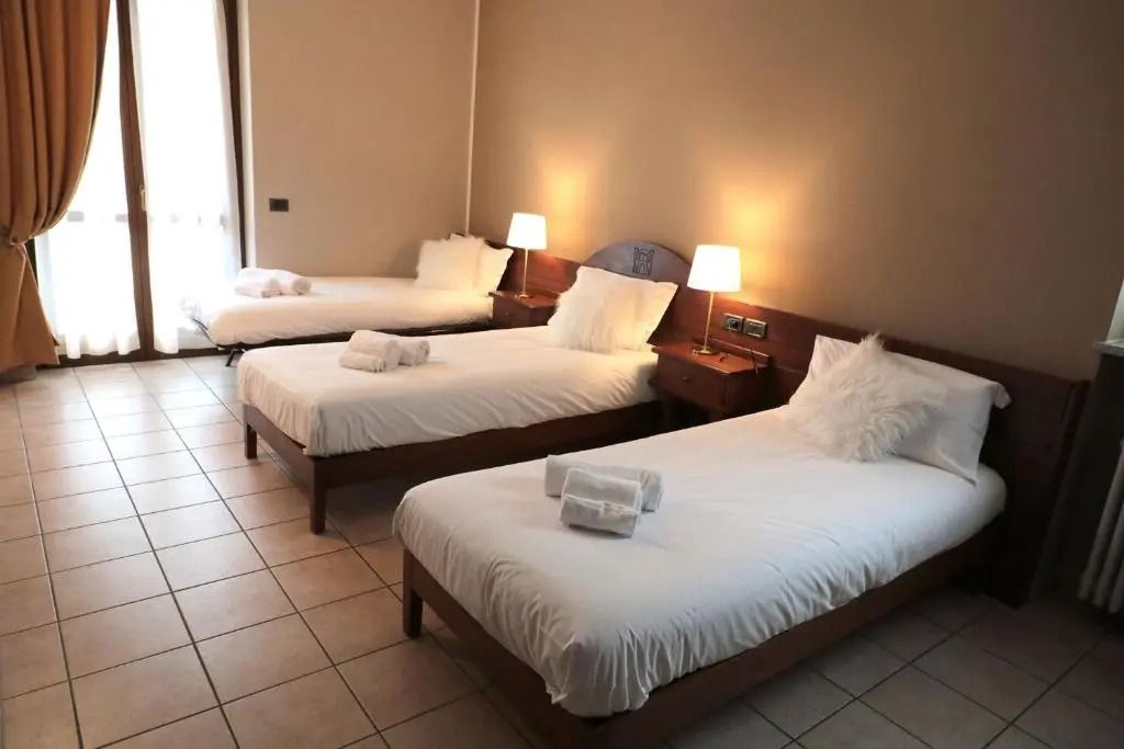 Gemütliches Hotelzimmer mit drei Einzelbetten und weicher Beleuchtung