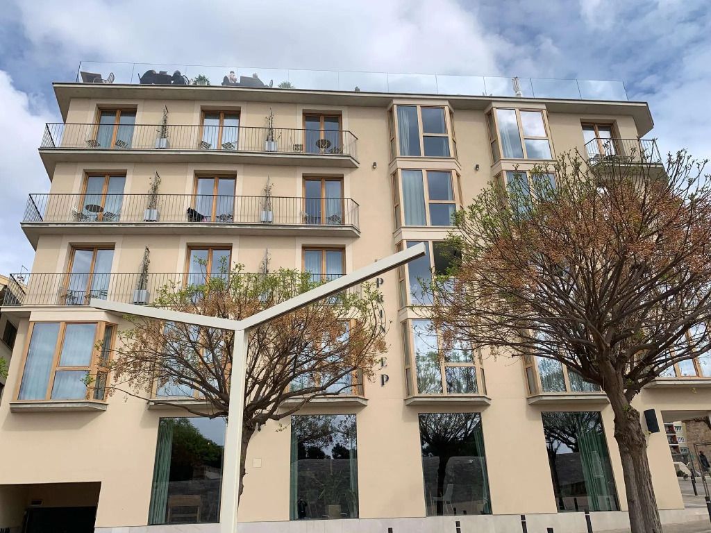 Fassade von Es Príncep Hotel mit Balkonen und Bäumen.