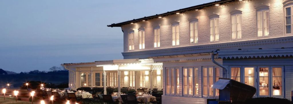 Elegante Hotel-Außenfassade im Abendlicht mit beleuchtetem Außenbereich