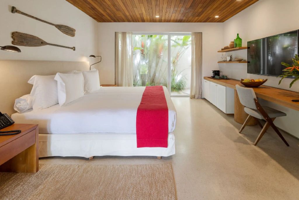 Helles Zimmer mit Doppelbett, roten Akzenten und Blick in den Garten