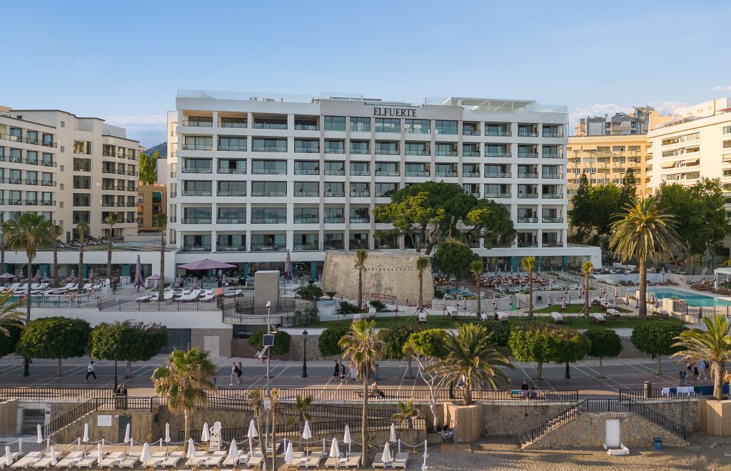Außenansicht des Hotel El Fuerte Marbella mit Palmen und Strand im Vordergrund