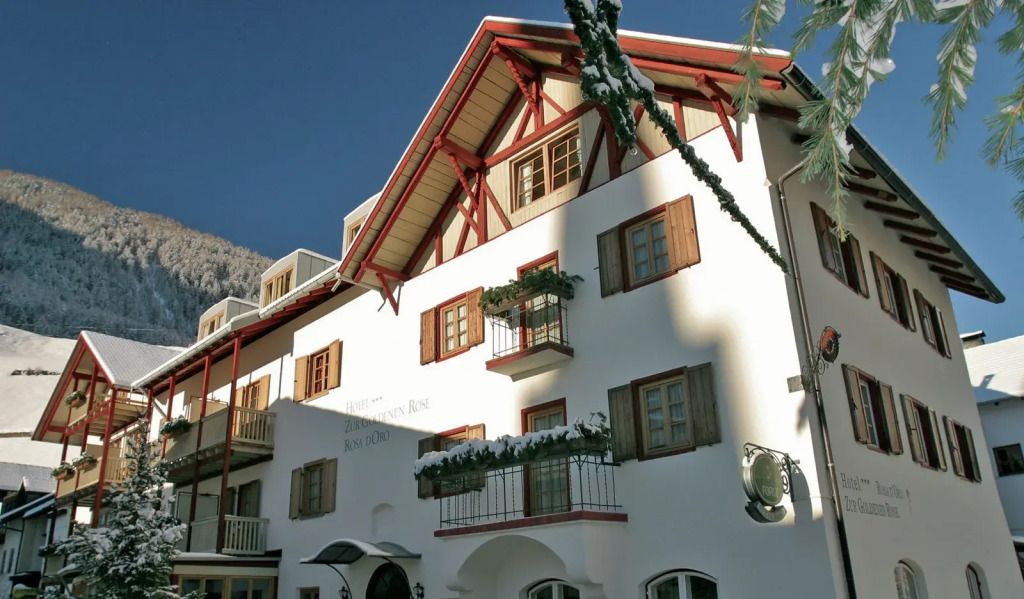 Traditionelle Alpenfassade mit roten Holzbalken und Schneebedeckungen