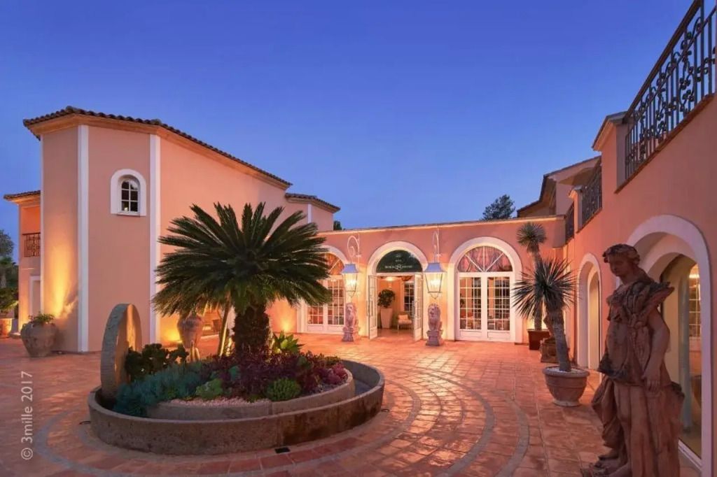 Abendstimmung vor der eleganten Fassade des Hotels mit Palmen und runden Eingangsbögen.