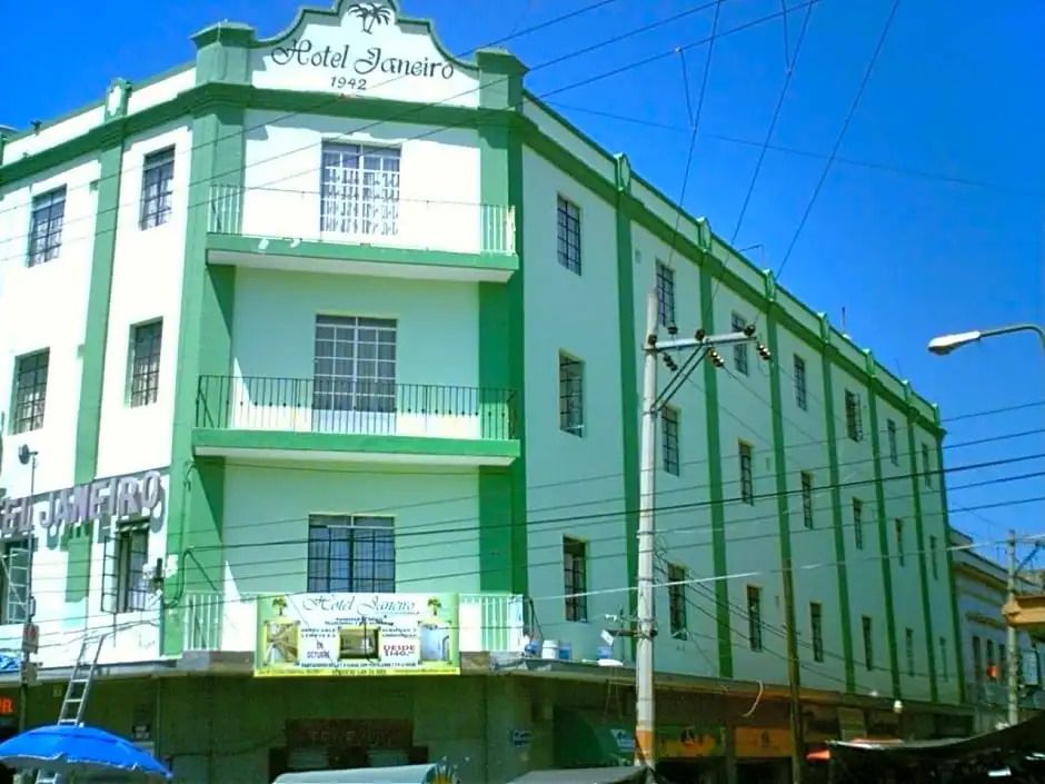 Grüne Fassade eines mehrstöckigen Gebäudes mit Balkonen und Schriftzug.