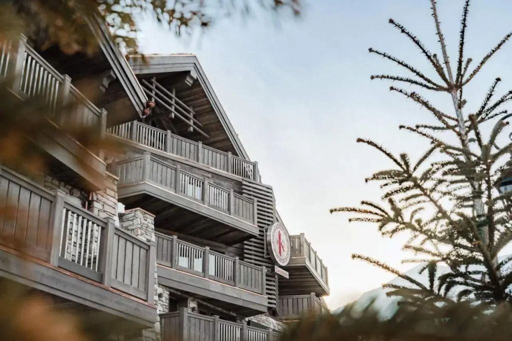 Alpenchalet-Architektur am frühen Morgen mit Holzbalkonen und Bergblick.